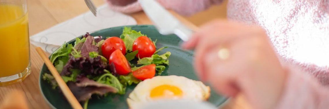 Enjoy a nutritious breakfast with greens, fried egg, and fresh orange juice for a healthy start to your day.